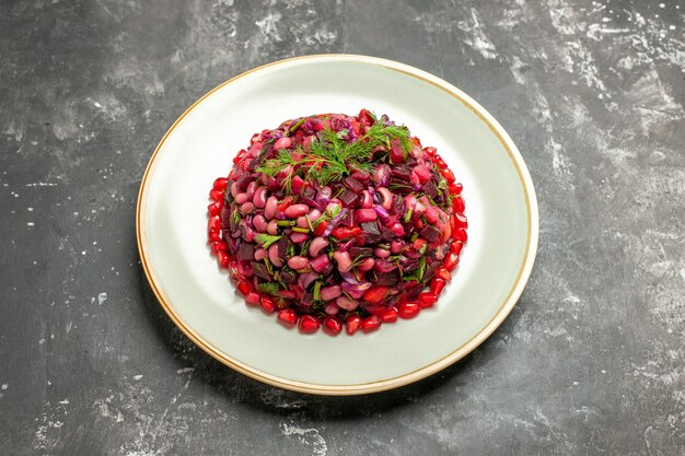 Vue avant de la salade de vinaigrette aux grenades et haricots sur le fond sombre