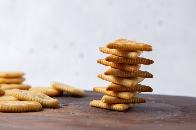 Vue avant de savoureuses chips salées bordées de bureau en bois et snack croustillant de cracker léger