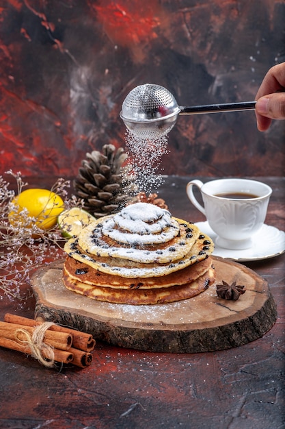 Vue avant de savoureuses crêpes sucrées avec du sucre en poudre sur fond sombre