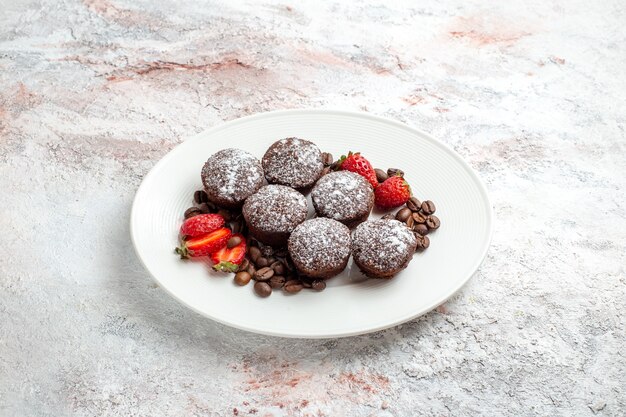 Vue avant de savoureux gâteaux au chocolat avec des fraises et des pépites de chocolat sur la surface blanche du gâteau biscuit cuire au four biscuit tarte sucrée