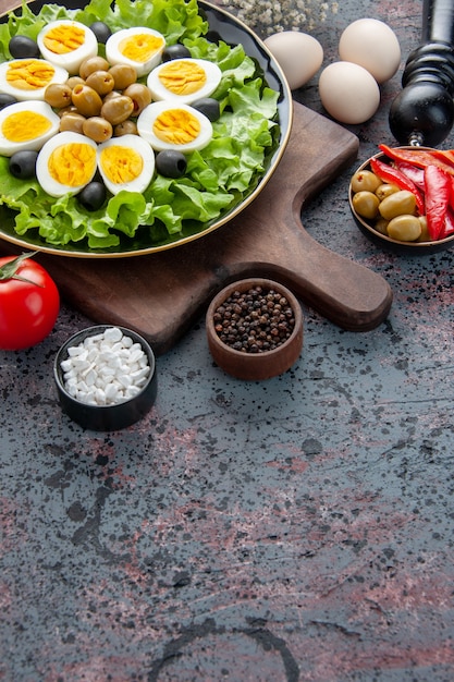 Vue avant de savoureux œufs durs avec salade verte et olives sur fond clair