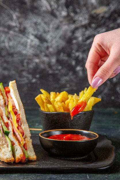 Vue avant de savoureux sandwichs au jambon avec frites surface sombre