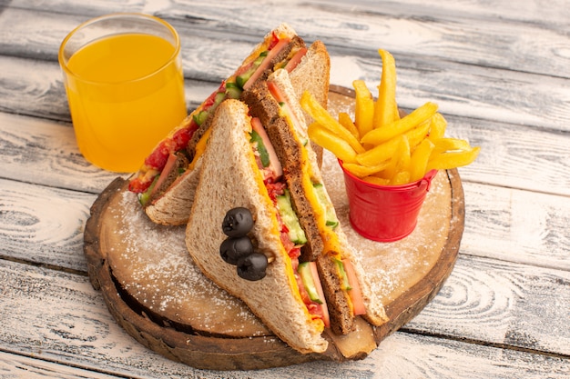 Vue avant de savoureux sandwichs au pain grillé avec du jambon au fromage à l'intérieur avec du jus de frites sur bois