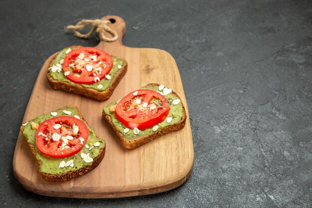 Vue avant de savoureux sandwichs à l'avocat avec des tranches de tomates rouges