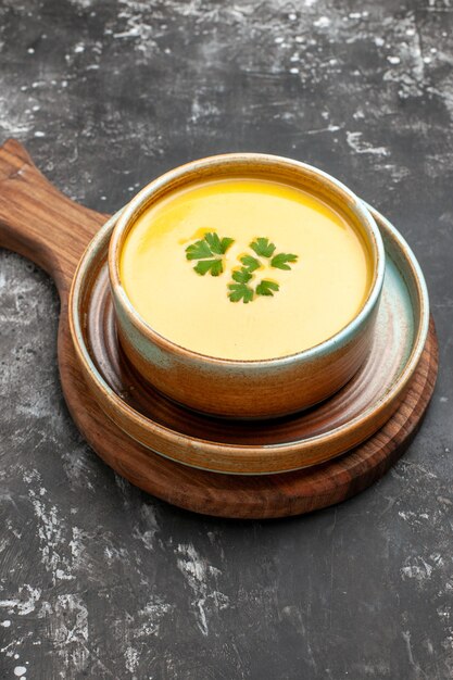 Vue avant de la soupe à la citrouille à l'intérieur de la plaque sur la table sombre