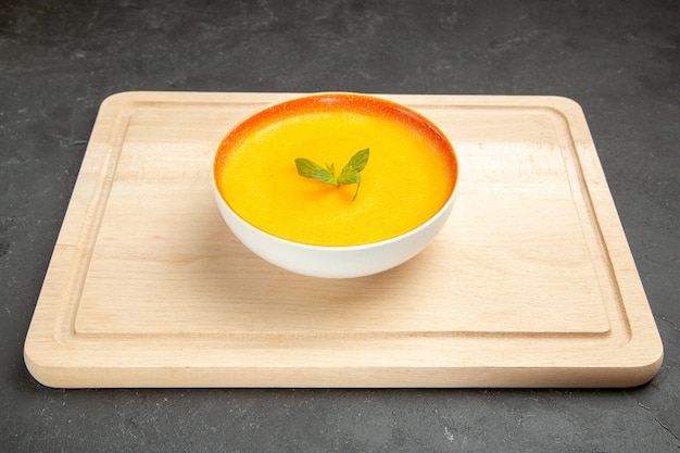 Vue avant de la soupe à la citrouille savoureuse à l'intérieur de la plaque sur la couleur de la soupe de bureau léger