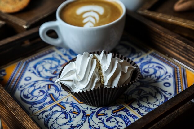 Vue avant de la tasse de cappuccino avec meringue sur un plateau