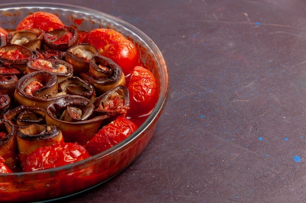 Vue avant des tomates et des aubergines repas de légumes cuits sur la surface sombre