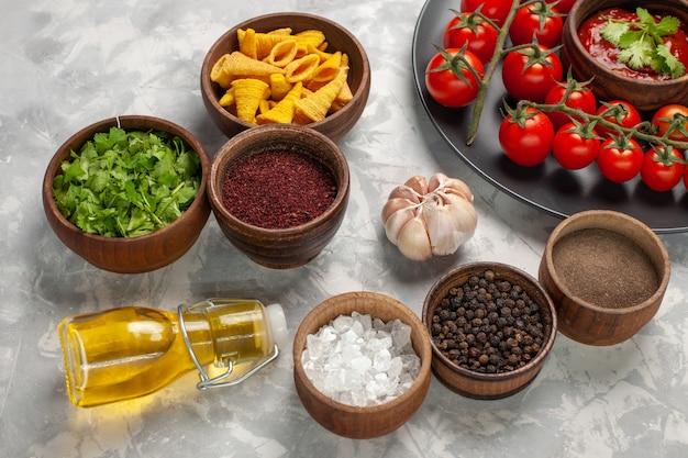 Photo gratuite vue avant des tomates cerises fraîches à l'intérieur de la plaque avec différents assaisonnements sur surface blanche salade alimentaire repas de légumes