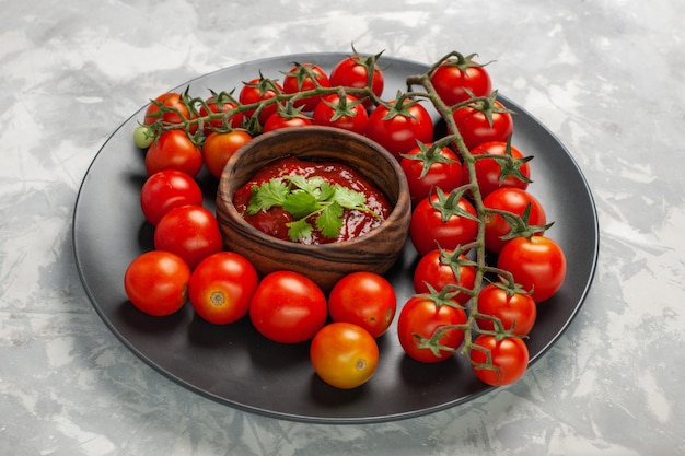 Photo gratuite vue avant des tomates cerises fraîches à l'intérieur de la plaque avec sauce tomate sur la surface blanche salade de légumes repas nourriture santé