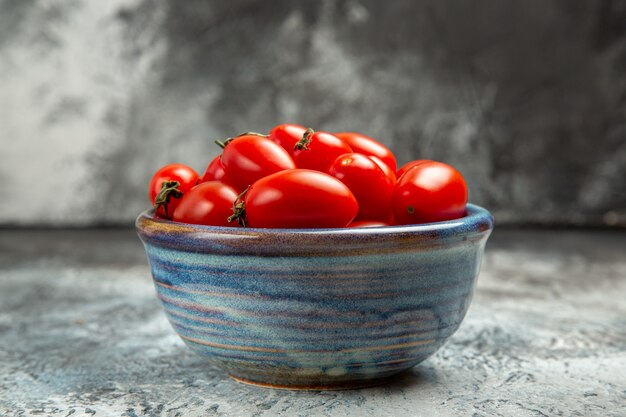 Vue avant des tomates rouges fraîches à l'intérieur de la plaque sur le fond sombre-clair