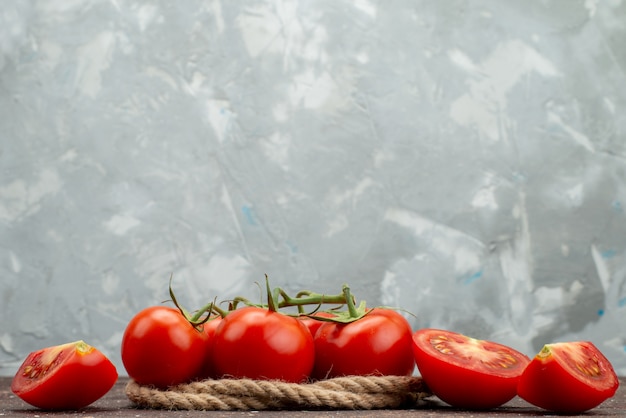 Vue avant de tomates rouges fraîches mûres et entières en tranches sur blanc, avec des cordes couleur alimentaire de fruits légumes berry
