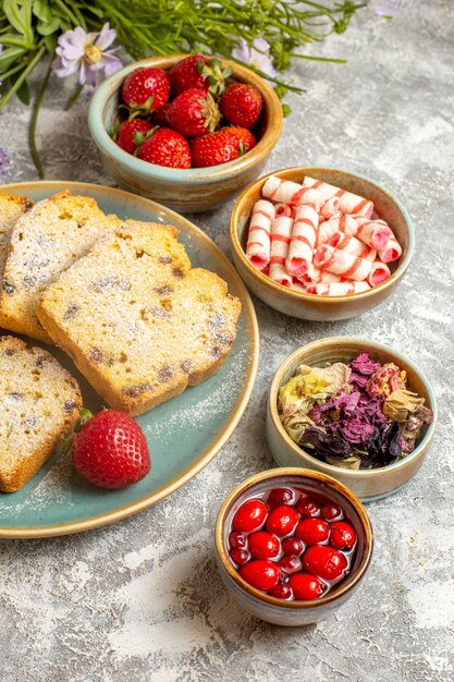 Vue avant des tranches de gâteau délicieux avec des fraises sur une surface légère tarte aux fruits sucrée