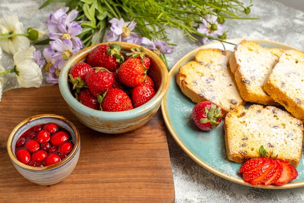 Vue avant des tranches de gâteau délicieux avec des fraises sur la tarte au gâteau sucré de surface légère