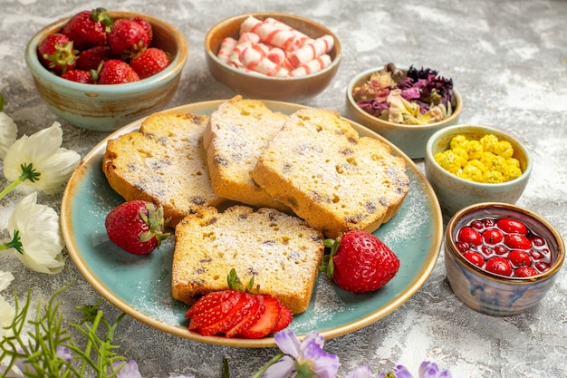 Vue avant des tranches de gâteau délicieux avec des fruits sur la surface légère gâteau à tarte aux fruits sucré