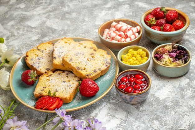 Vue avant des tranches de gâteau délicieux avec des fruits sur la surface légère gâteau à tarte fruits doux