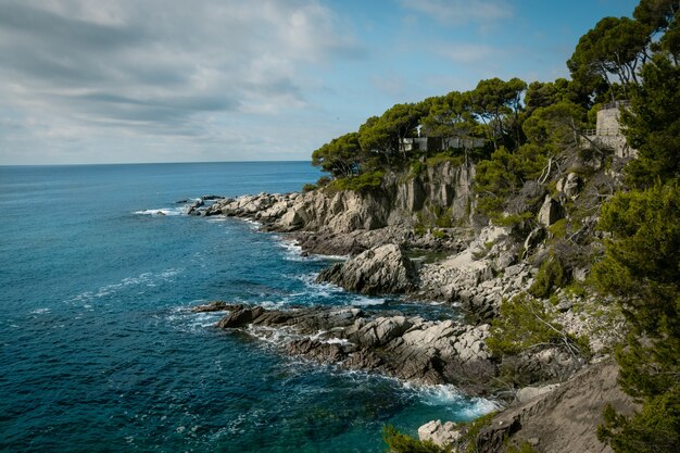 Vue d'un bord de mer rocheux avec un ciel bleu nuageux