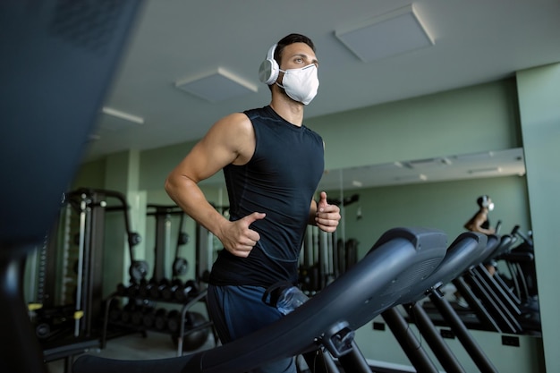 Vue ci-dessous d'un athlète avec masque de protection faisant du jogging sur une piste de course