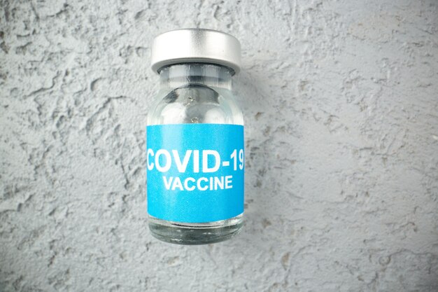 Vue ci-dessus de l'ampoule avec vaccin covid sur fond de sable gris avec espace libre