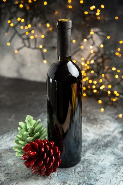 Vue ci-dessus de la bouteille de vin rouge pour la célébration et deux cônes de conifères sur fond sombre