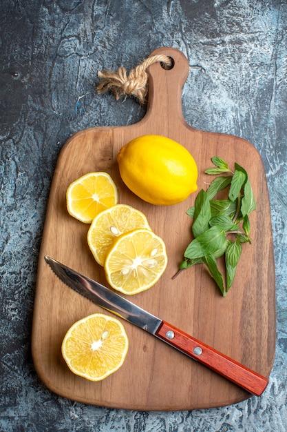 Vue ci-dessus des citrons frais et couteau à la menthe sur une planche à découper en bois