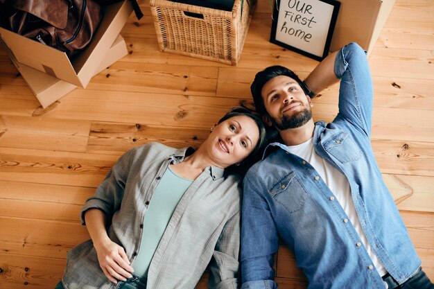 Vue ci-dessus d'un couple allongé sur le sol dans leur nouvelle maison