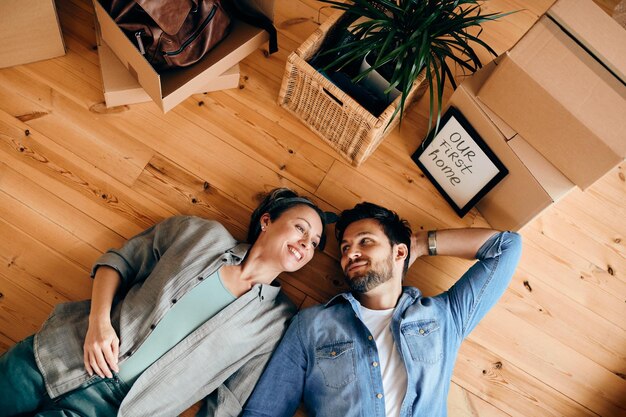 Vue ci-dessus d'un couple heureux se reposant sur le sol après avoir acheté sa première maison