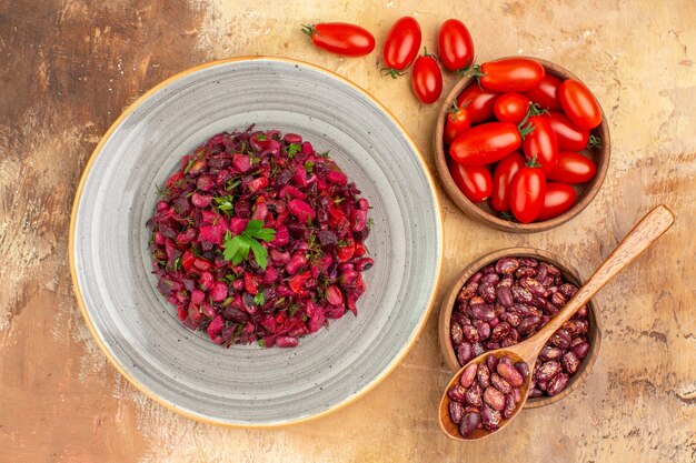 Vue ci-dessus d'une délicieuse salade de betteraves rouges, de haricots et de haricots à l'intérieur et à l'extérieur du pot et des tomates sur une table de couleurs mélangées