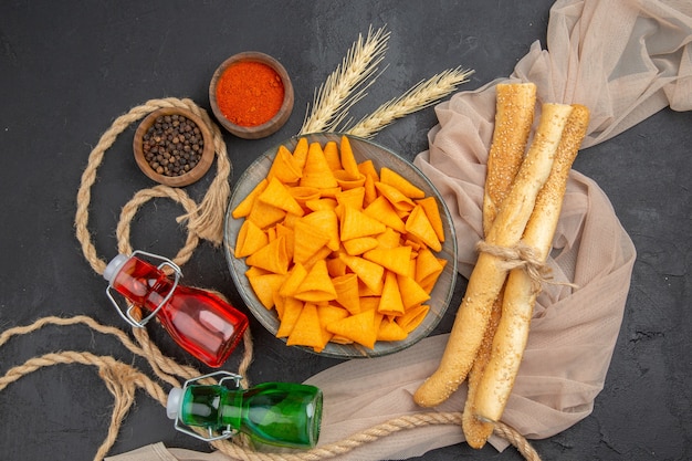 Photo gratuite vue ci-dessus de délicieuses frites bouteilles tombées poivrons sur serviette et corde sur fond noir