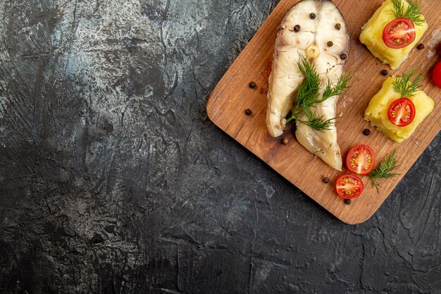 Vue ci-dessus du repas de sarrasin de poisson bouilli servi avec des tomates fromage vert sur une planche à découper en bois sur la surface de la glace