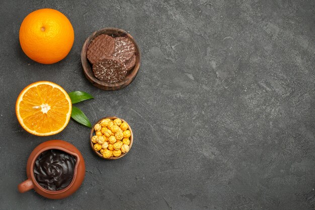 Vue ci-dessus de l'ensemble et coupé en deux oranges fraîches et biscuits sur table sombre