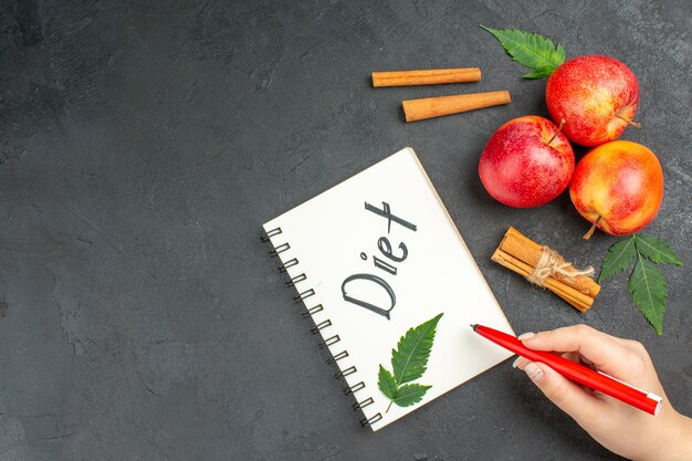 Vue ci-dessus des pommes fraîches biologiques naturelles avec des feuilles vertes cahier cannelle limes avec inscription de régime sur fond noir