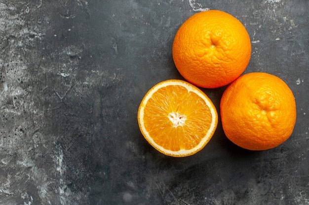 Vue ci-dessus de la source de vitamines coupée et des oranges fraîches entières sur fond gris