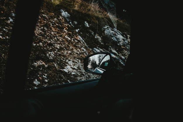 Vue sur les collines couvertes de neige et les arbres capturés à partir d'une fenêtre de voiture et du rétroviseur latéral