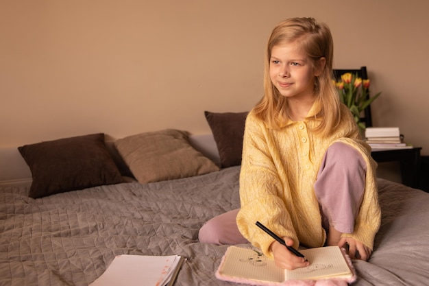 Vue complète de la jolie fille assise dans la chambre regarde la caméra et souriant