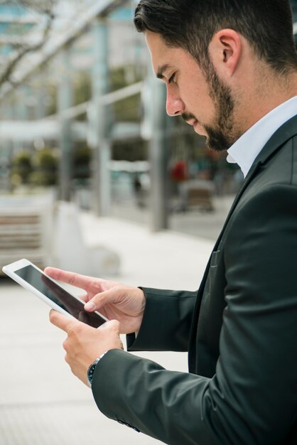 Vue de côté d&#39;un beau jeune homme d&#39;affaires à l&#39;aide de téléphone intelligent sur fond de flou