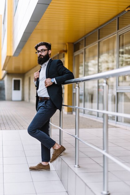 Vue de côté d&#39;un beau jeune homme d&#39;affaires, debout près de la rambarde