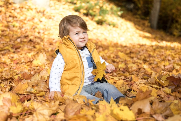 Vue de côté bébé assis dans les feuilles