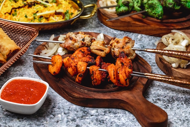 Vue de côté brochette d'agneau aux crevettes oignon grillé et sauce sur une planche