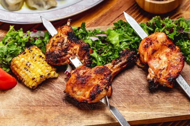 Vue de côté brochette de poulet avec laitue verte tomate oignon rouge grillé maïs et épine-vinette séchée sur la table