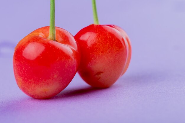 Photo gratuite vue de côté de la cerise des pluies mûres isolé sur la couleur lilas