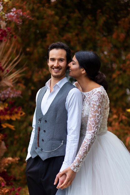 Vue de côté couple smiley posant au mariage