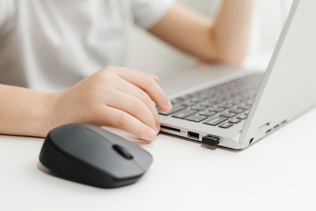 Vue de côté enfant utilisant un ordinateur portable et une souris