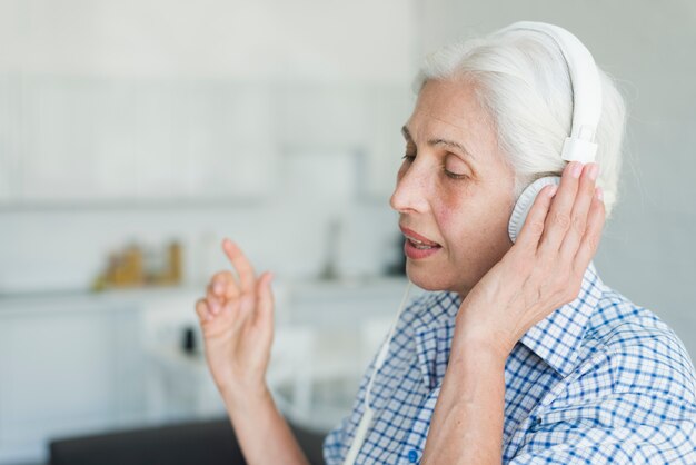 Vue côté, de, femme aînée, écoute musique, sur, casque, chant