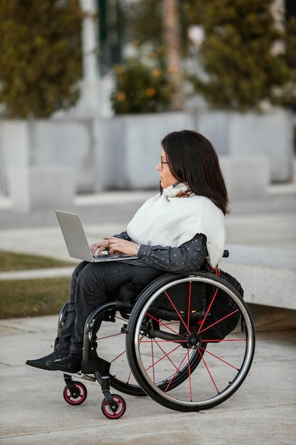 Vue côté, de, femme, dans, a, fauteuil roulant, à, ordinateur portable