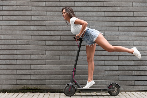 Vue côté, de, femme heureuse, poser, sur, scooter électrique