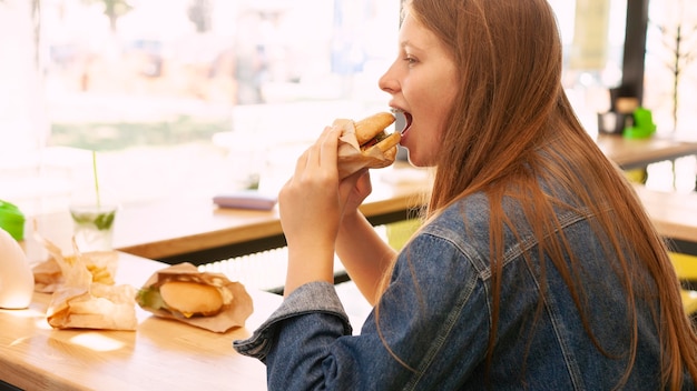 Vue côté, de, femme mange, hamburger