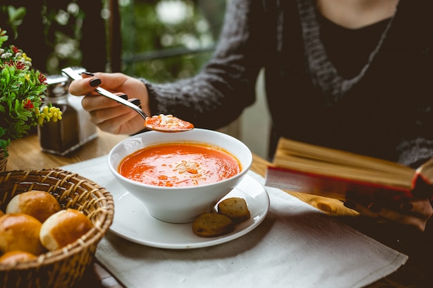 Vue côté, de, a, femme mange, soupe tomate, à, toasts, table