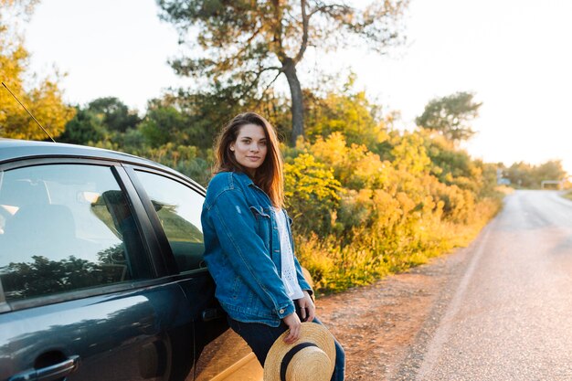 Vue côté, de, femme, poser, dehors, côté, voiture