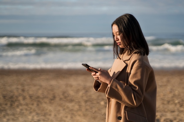 Photo gratuite vue côté, femme, tenue, smartphone